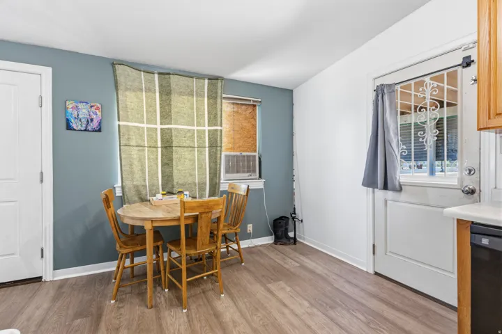Wood-finish flooring, white paneled door, and a partially visible built-in dishwasher