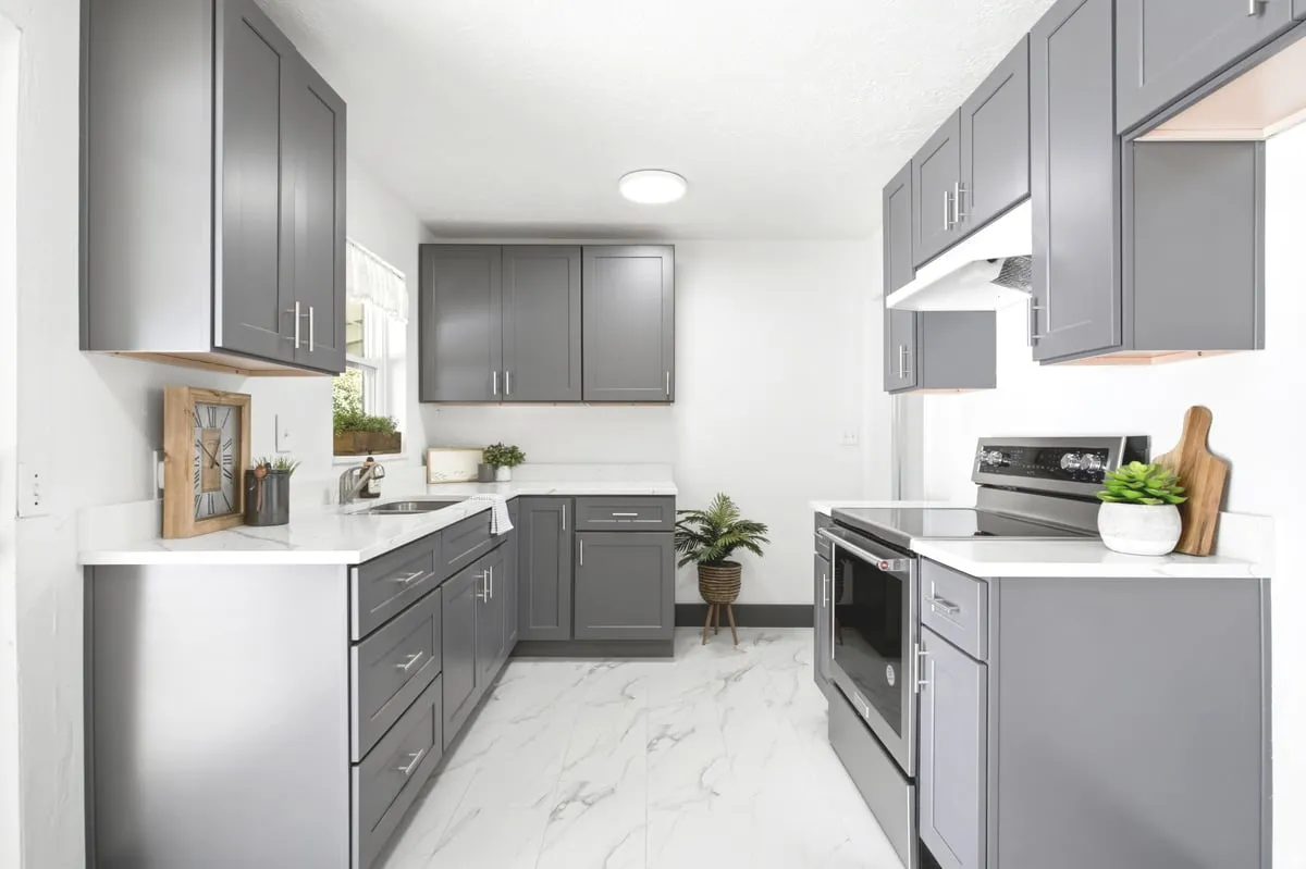 Galley kitchen featuring gray cabinetry, stainless steel appliances, white countertops, and white tile flooring
