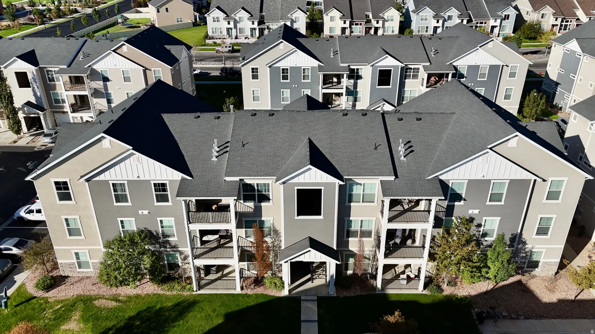Multi-story residential building with private balconies and a dark shingle roof
