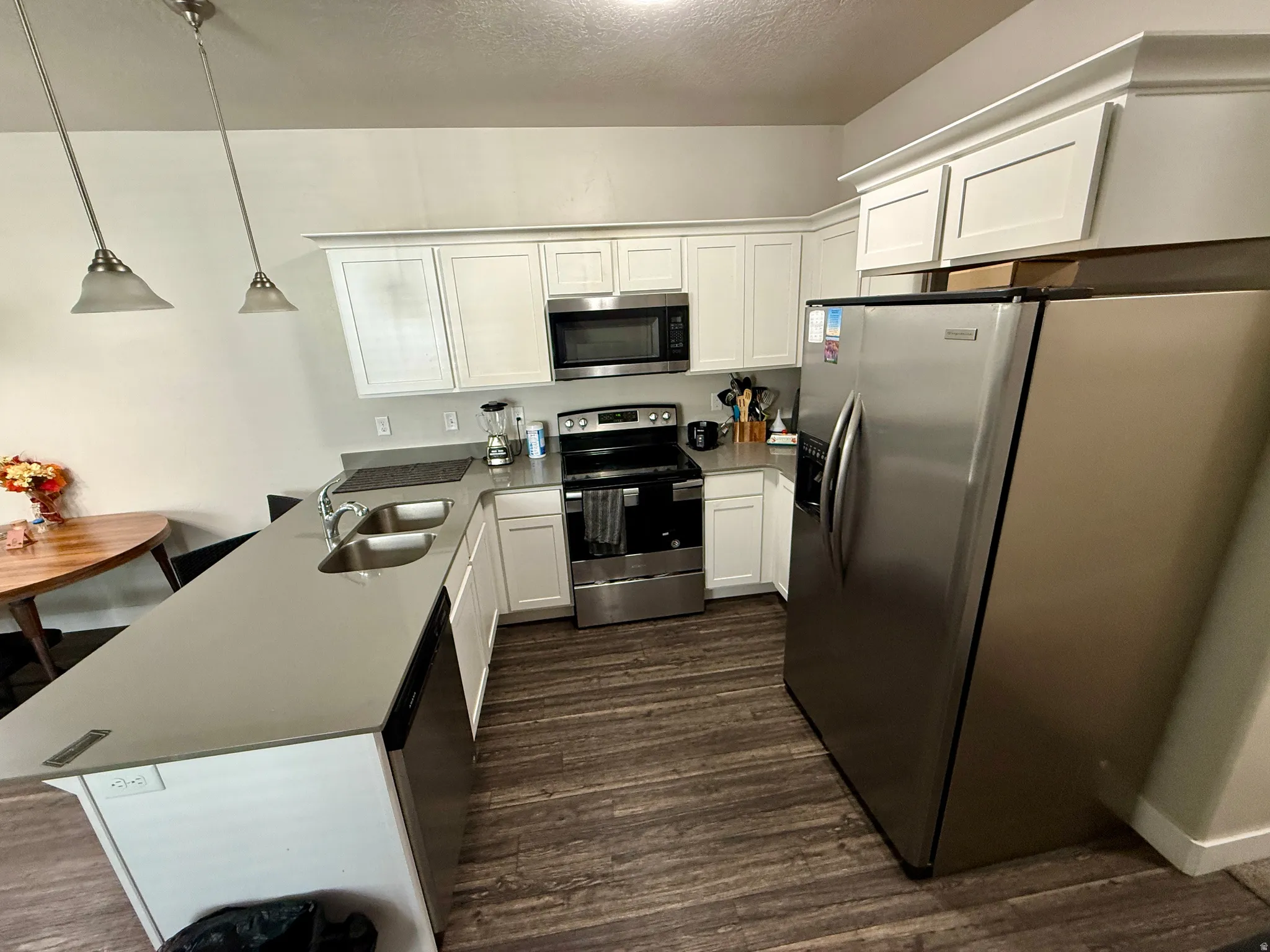 Kitchen featuring white shaker-style cabinetry, stainless steel appliances, a double basin sink, and wood-finish flooring