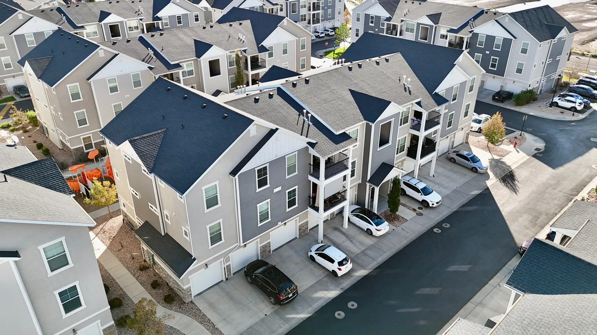 Multi-story residential buildings featuring gabled roofs, balconies, and attached garages