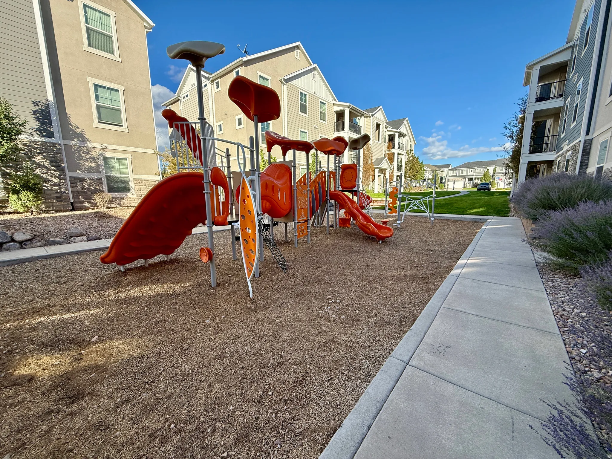 Outdoor playground featuring slides and climbing elements, surrounded by wood chip surfacing