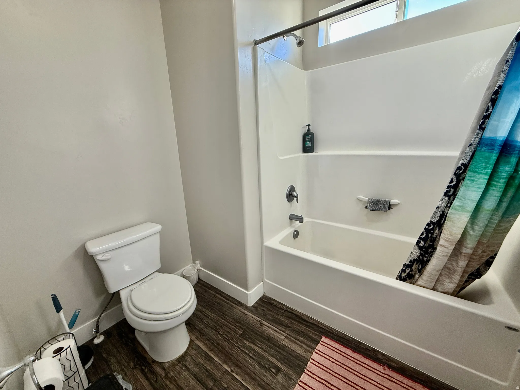 Tub and shower combination with a single-handle faucet, integrated shelving, and a white toilet