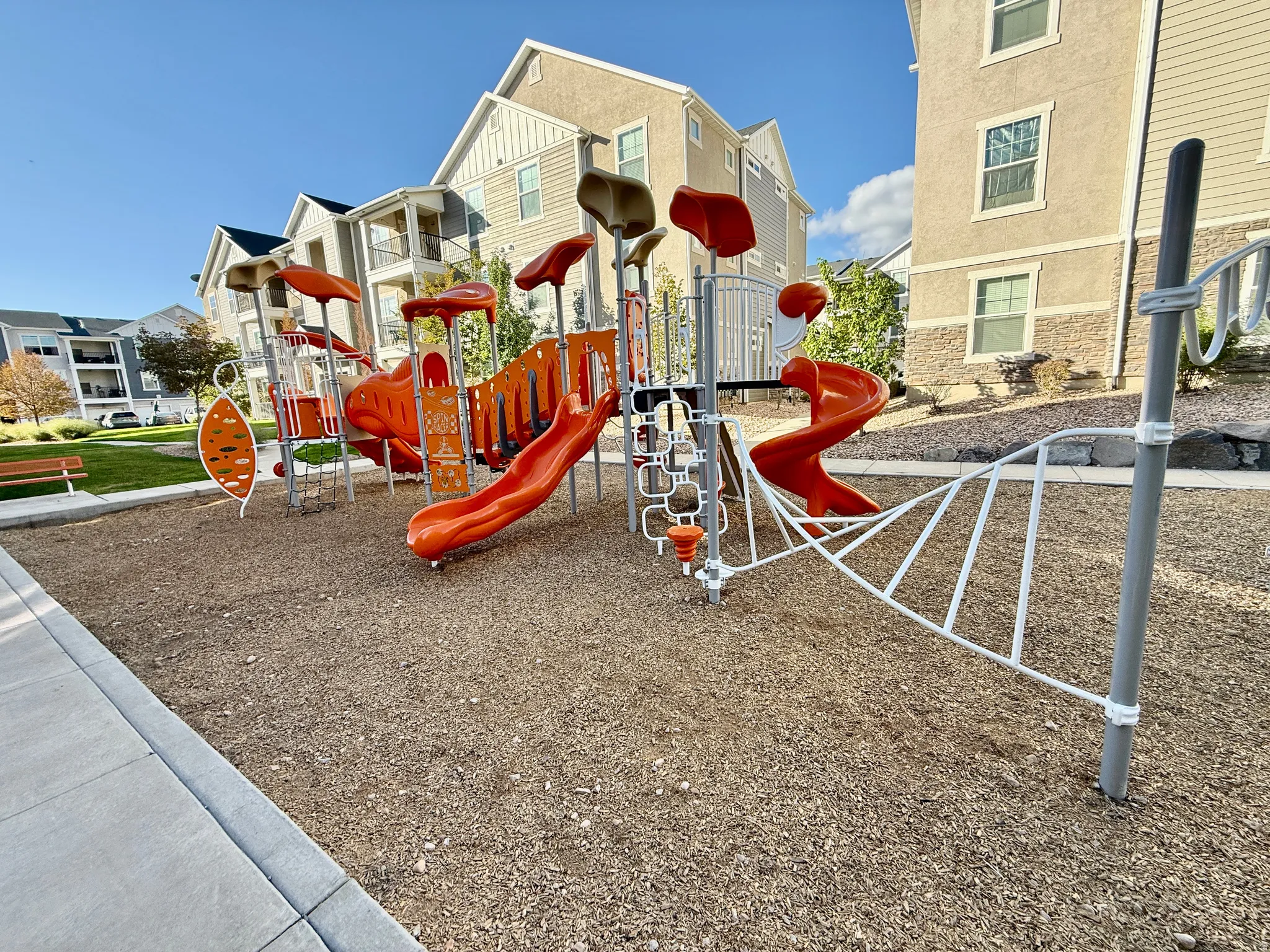 Playground area featuring multiple slides, climbing structures, and a wood chip surface