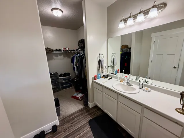 Vanity featuring a single-bowl sink, white cabinetry, and a large mirror