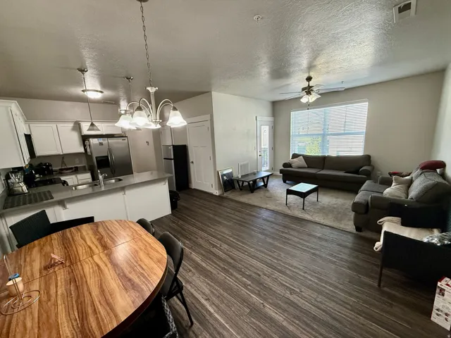Open concept living area featuring wood-finish flooring, a ceiling fan, and a large window with blinds