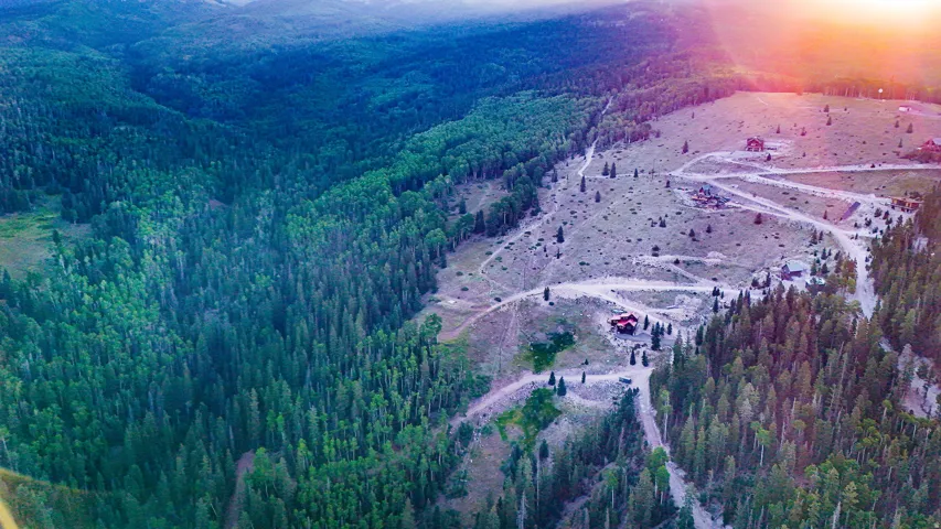 Expansive mountain terrain featuring dense evergreen forests and multiple structures