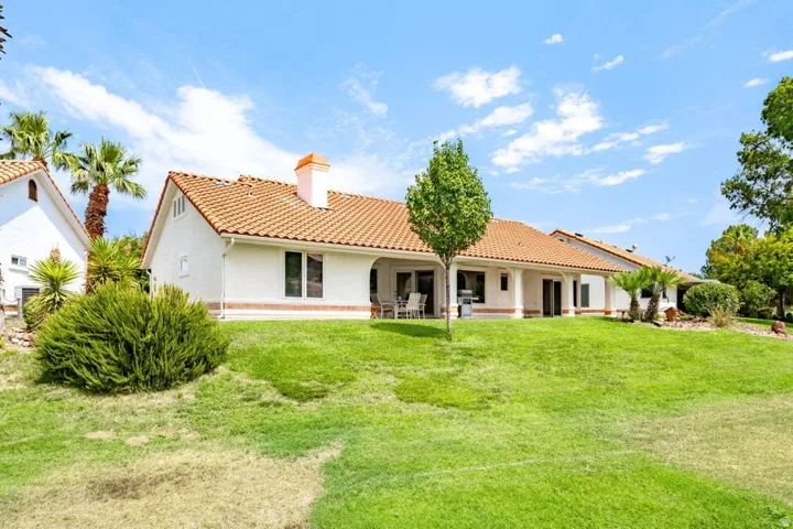 Expansive green lawn with mature landscaping, featuring a white stucco exterior and a terracotta tile roof