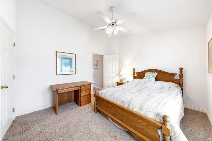Vaulted ceiling with a ceiling fan, white paneled doors, and neutral carpeting