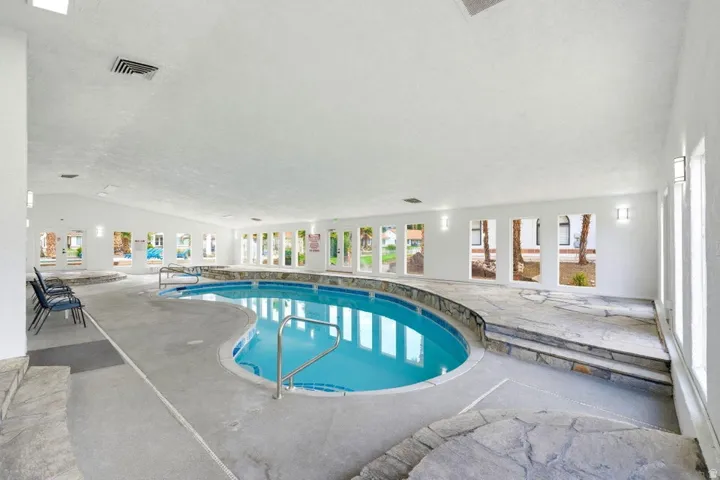 Indoor swimming pool with light blue water, curved shape, and stainless steel handrails