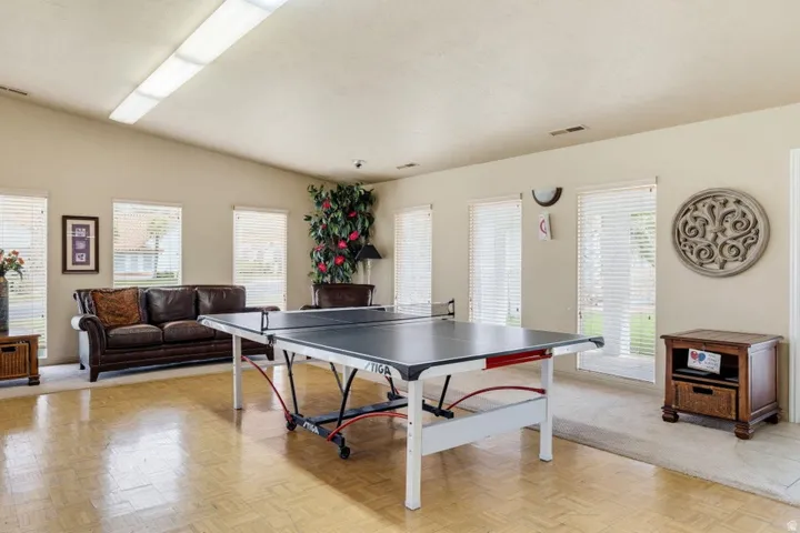Spacious room with wood-finish flooring, vaulted ceiling, and multiple windows with blinds