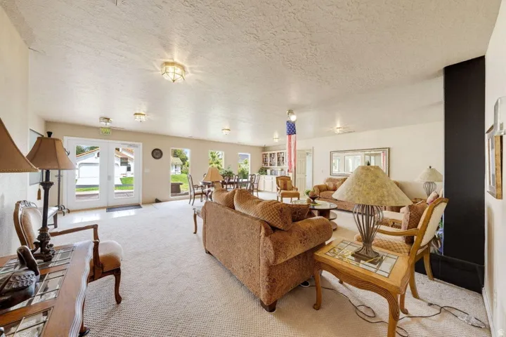 Spacious interior with neutral-toned walls, recessed lighting, and a large carpeted area