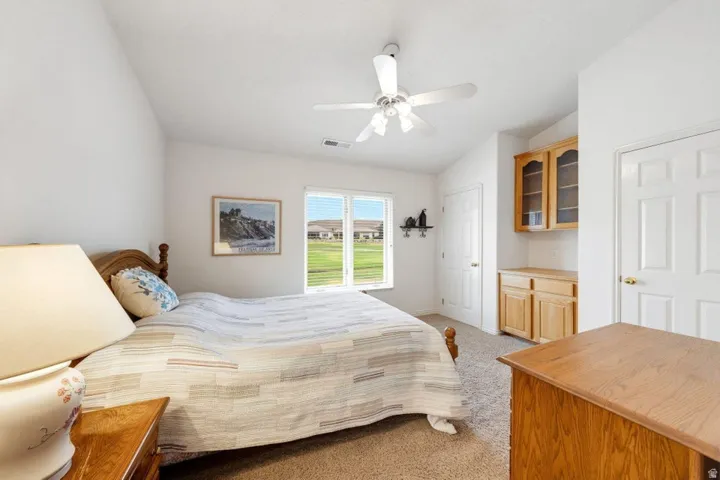Recessed window offering natural light, built-in cabinetry with glass-front uppers, white ceiling fan, and painted white six-panel doors