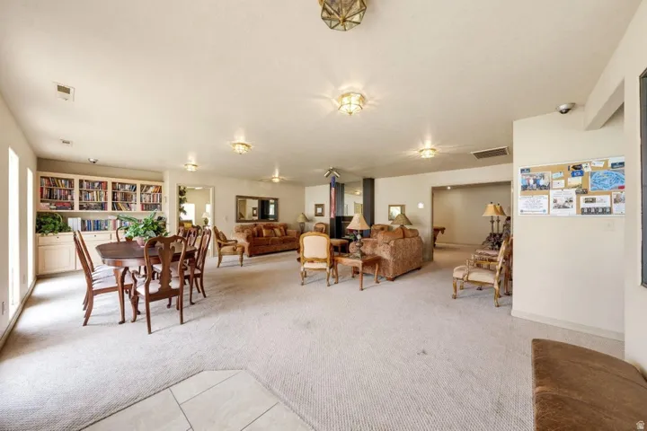 Expansive carpeted room featuring built-in cabinetry, recessed lighting, and multiple distinct areas