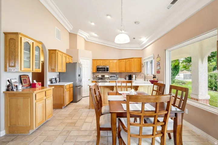 Recessed lighting, crown molding, tile flooring, wood cabinetry, and a large picture window
