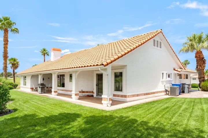 Exterior featuring a terracotta tile roof, white stucco finish, extended covered patio, and large glass sliding doors