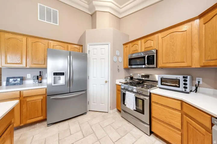 Kitchen featuring light wood cabinetry, light-toned countertops, stainless steel appliances, and tiled flooring