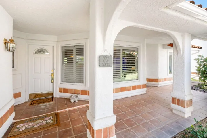 Arched entryways, white stucco exterior, terracotta tile flooring, decorative exterior lighting, and window shutters