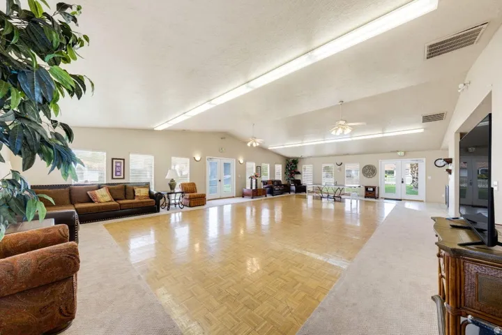 Vaulted ceiling, recessed lighting, ceiling fans, multiple windows, and patio access