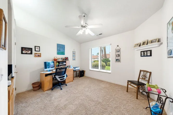 Vaulted ceiling with a ceiling fan, window with blinds, and wall-mounted shelving
