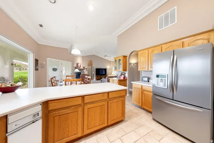 Kitchen featuring a stainless steel refrigerator, wood cabinetry, light-toned countertops, and tile flooring