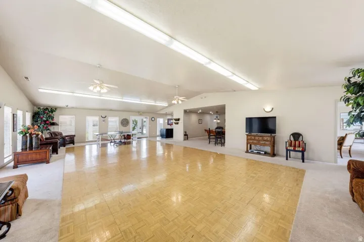 Expansive main area with parquet flooring, vaulted ceiling, recessed lighting, and multiple windows