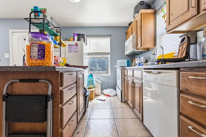Updated Kitchen featuring wood cabinetry, a built-in microwave, a stainless steel sink, a dishwasher, and tiled flooring