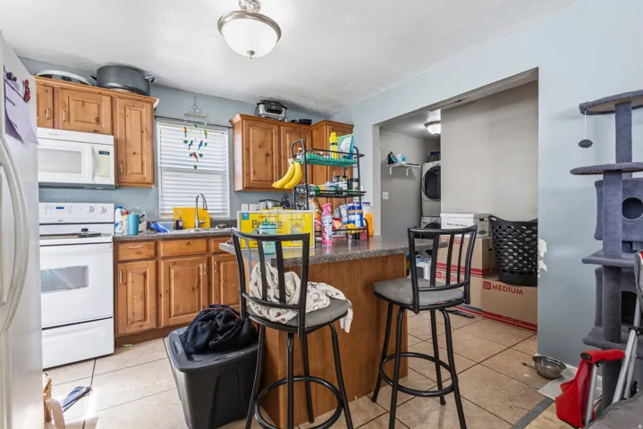 Kitchen featuring wood-finish cabinetry, white appliances, and a central island with a counter