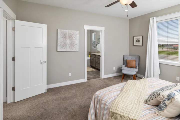 Neutral-toned wall finish, plush carpet flooring, white trim details, window with blinds, and an overhead ceiling fan