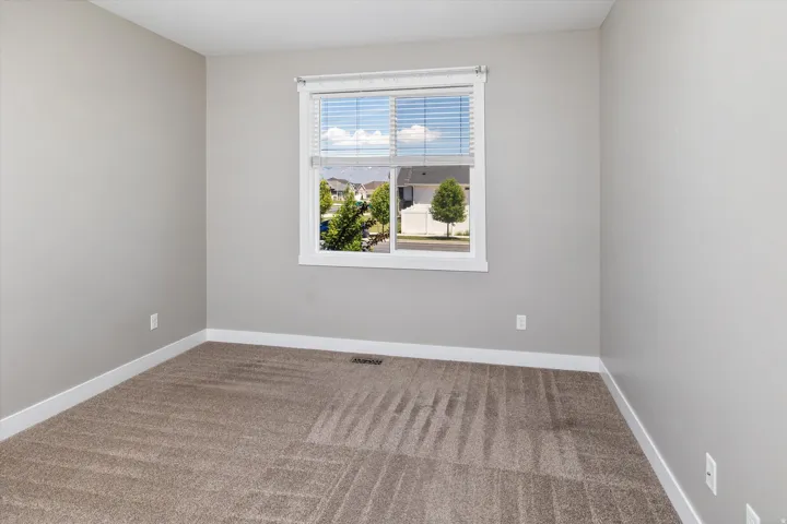 Neutral wall paint, plush carpeting, and a white-trimmed window with blinds
