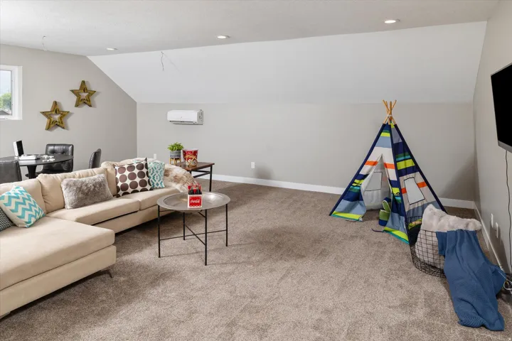 Carpeted flooring with recessed lighting, a window, and a wall-mounted climate control unit