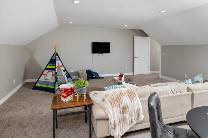 Carpeted room featuring recessed lighting, sloped ceilings, and a solid white door with a contemporary handle