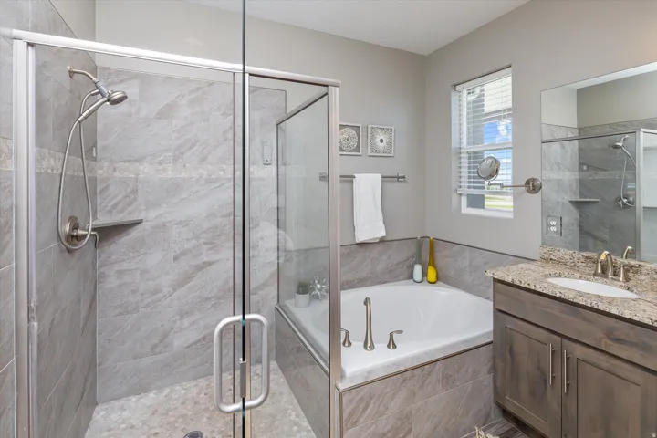 Shower enclosure with glass door, tiled walls, and pebble-finish floor