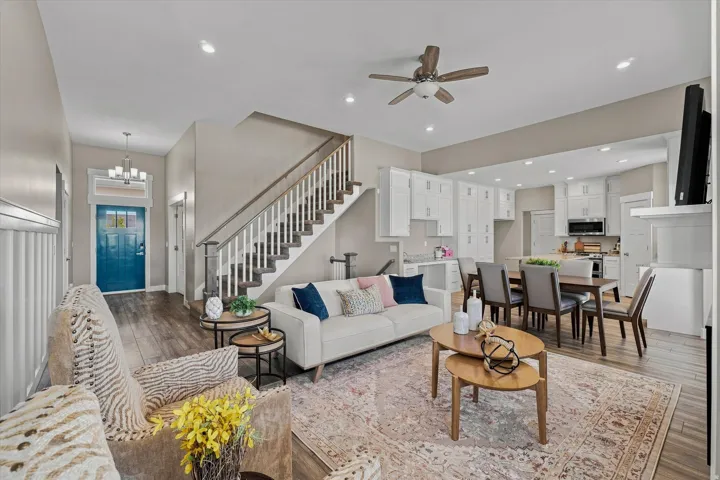 Open-concept living area featuring wood-finish flooring, a contemporary staircase with white risers, and recessed lighting