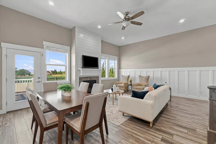 Wood-finish flooring, white board-and-batten accent wall, shiplap fireplace surround, recessed lighting, and a ceiling fan
