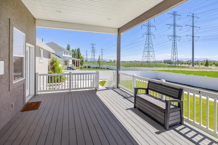 Covered patio featuring composite decking, white railing, and a private exterior door