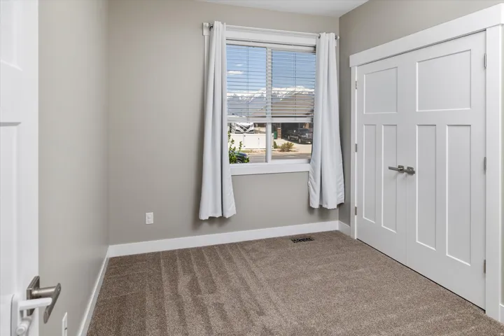 Recessed window with white blinds, neutral wall tones, and textured carpeting