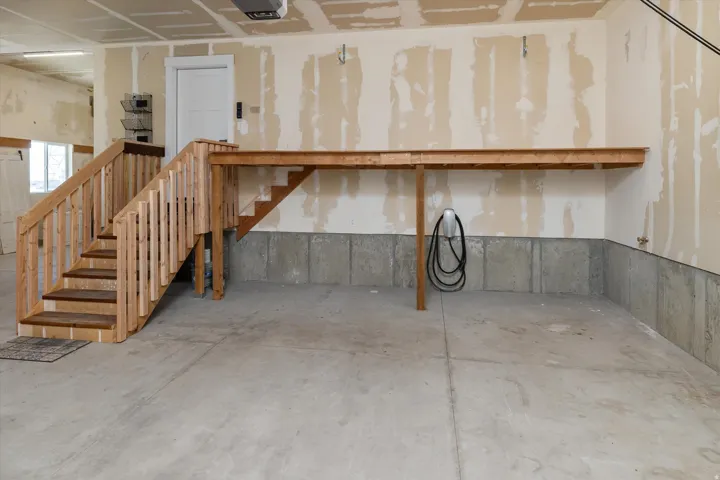 Concrete flooring, built-in wooden staircase, built-in wooden shelving, white door, concrete foundation