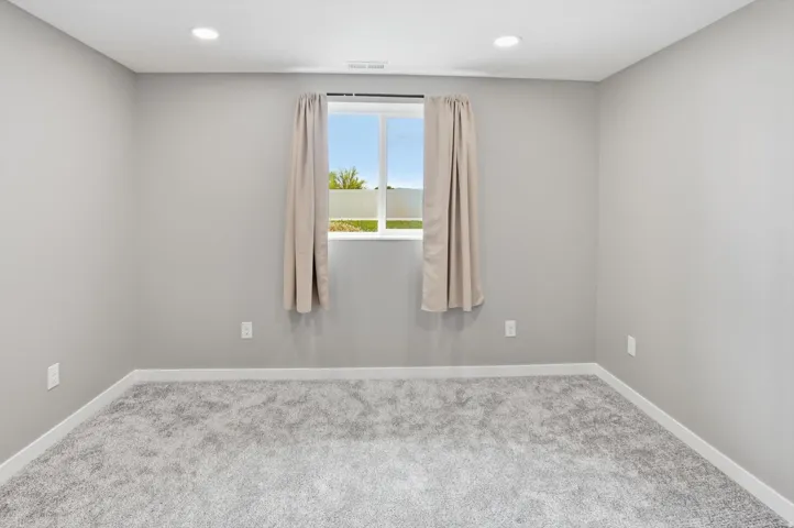Recessed lighting, light gray walls, gray carpet flooring, white trim, and a window with a white frame