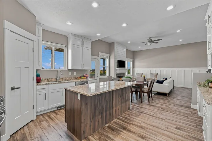 White shaker cabinetry, granite countertops, wood-finish flooring, recessed lighting, and a built-in fireplace