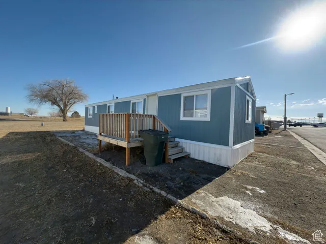 Blue exterior siding with white trim, elevated wood deck with railing, and white foundation skirting