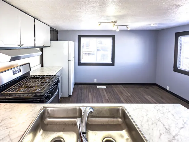 Kitchen featuring white upper cabinetry, stainless steel sink, and wood-finish flooring