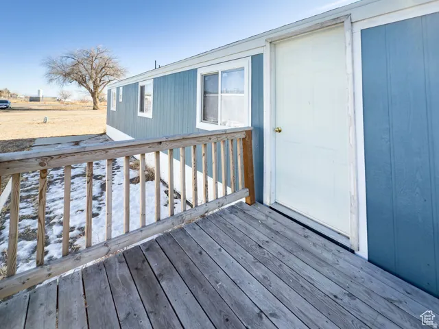 Exterior featuring blue siding, white trim, multiple windows, and a wood-finish deck with railings