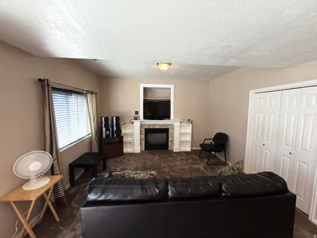 Built-in fireplace with a tile surround, window with blinds and drapes, and paneled closet doors
