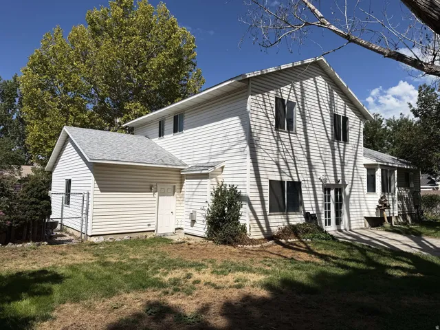 White siding exterior with multiple windows, a gabled roofline, and a prominent side addition