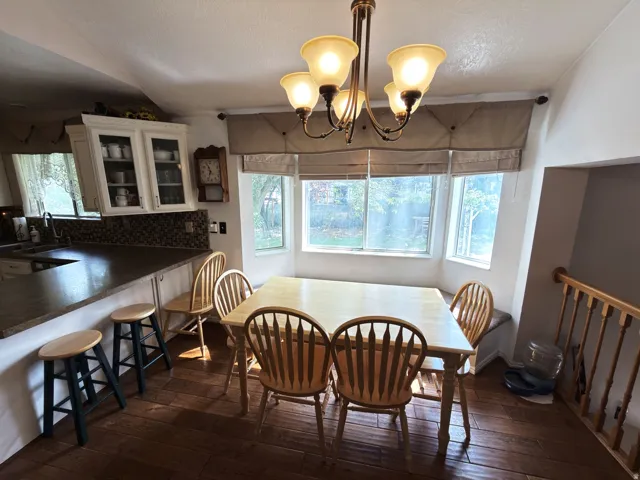 Bay window with built-in bench seating, wood-finish flooring, and a multi-light chandelier