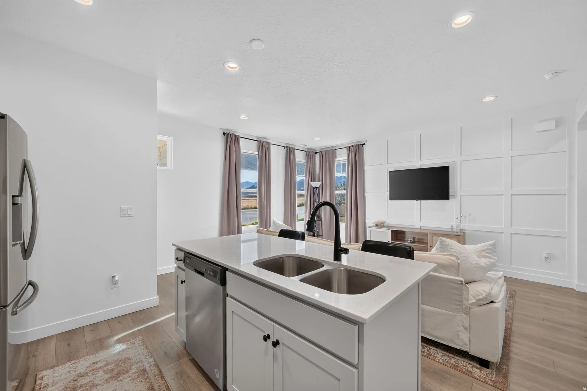 Kitchen island with dual stainless steel sinks, a matte black faucet, and light-toned countertops