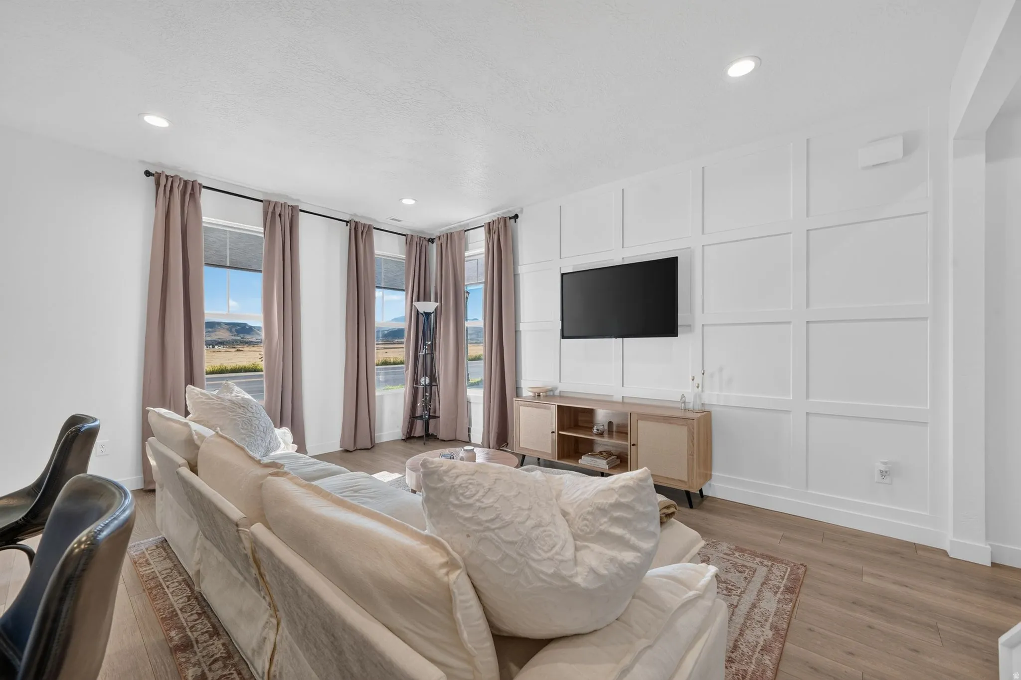 Wood-finish flooring, recessed lighting, and a feature wall with decorative paneling