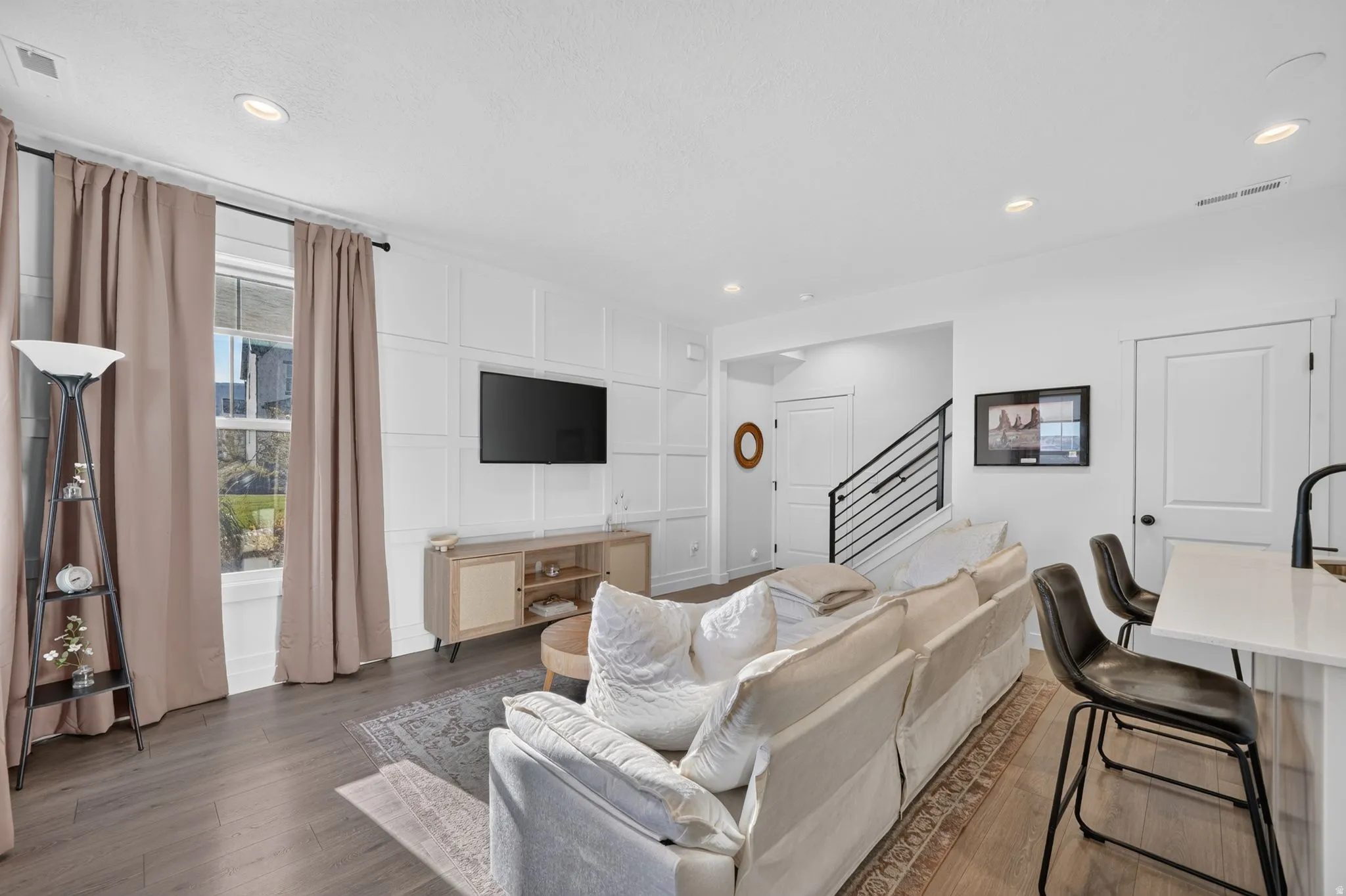 Open-concept living area featuring a decorative accent wall, recessed lighting, and wood-finish flooring