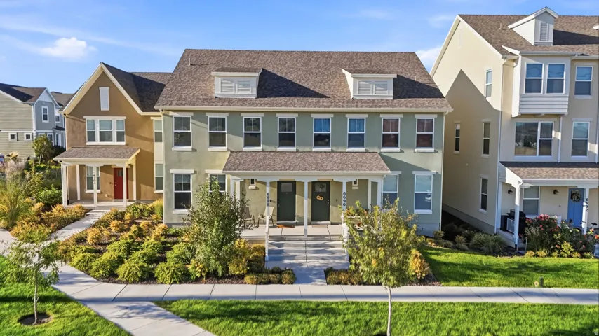 Pitched roofline with dormer windows, covered front porches, and established landscaping